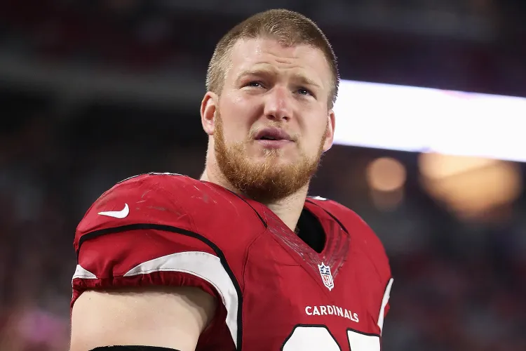Josh Mauro wearing Arizona Cardinals uniform standing on field during NFL match with blurred crowd behind