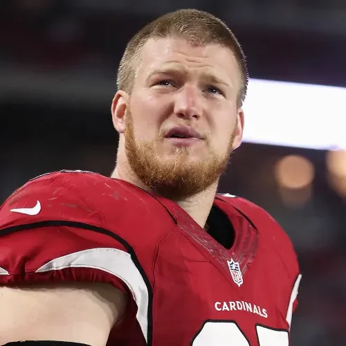 Josh Mauro wearing Arizona Cardinals uniform standing on field during NFL match with blurred crowd behind